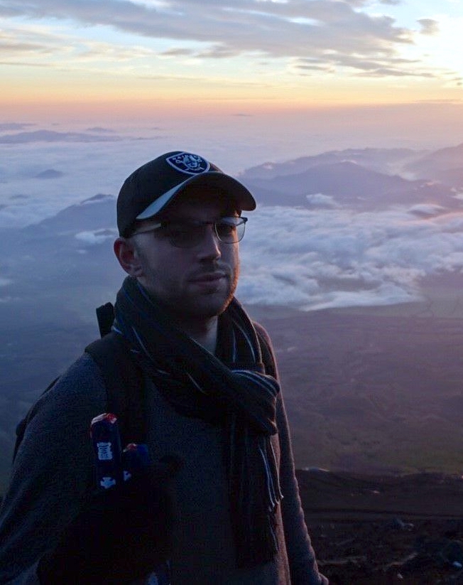 Jack wearing a hat and glasses atop Mt Fuji, Japan.